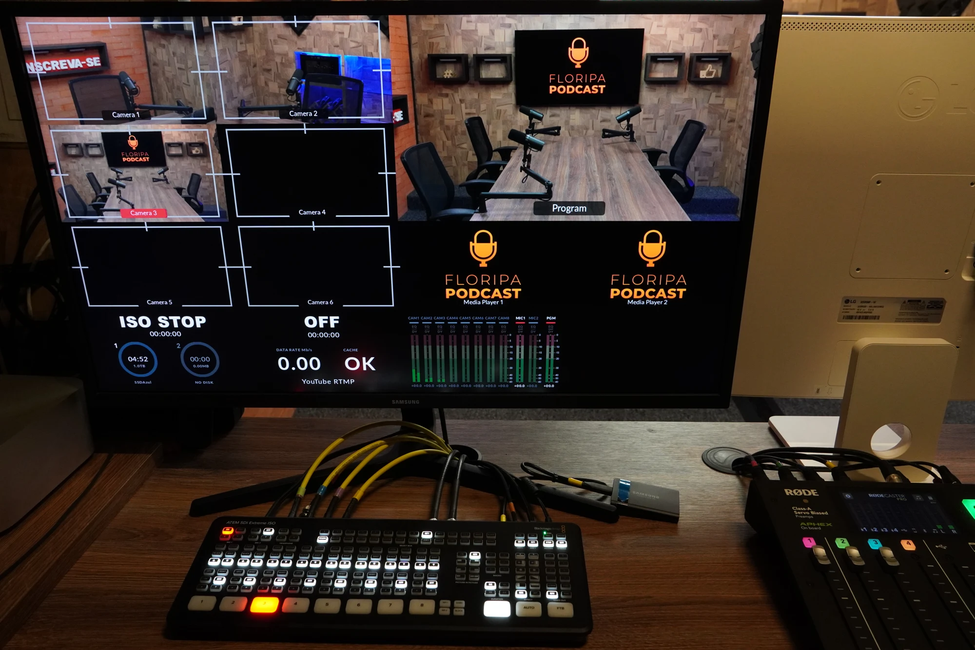 Mesa de controle de áudio com o cenário do podcast ao fundo